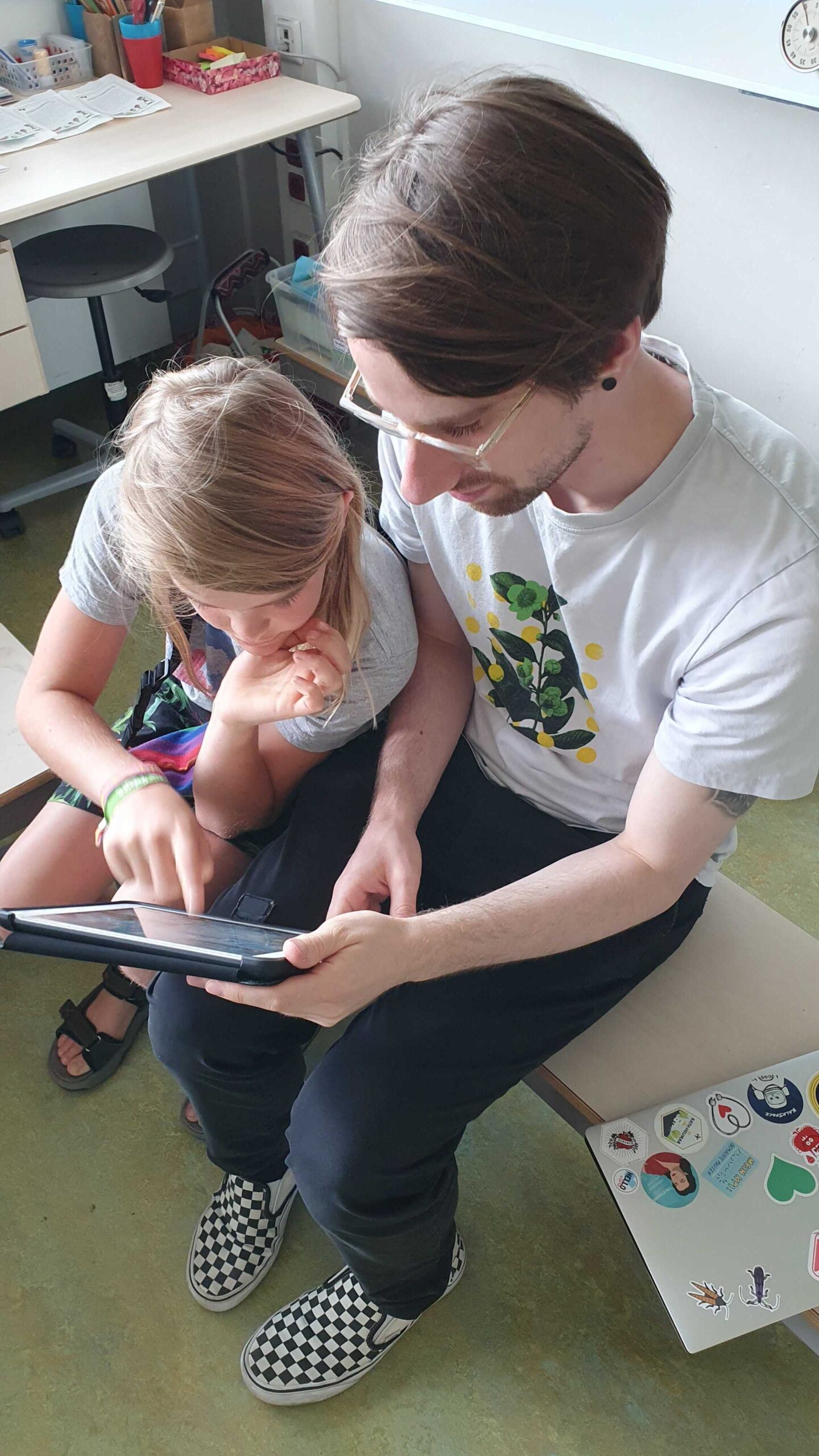 Unser Programmierer Jannik zusammen mit einem Schüler sitzen nebeneinander und schauen sich auf dem IPad die Website 'Programmieren mit der Maus' an.