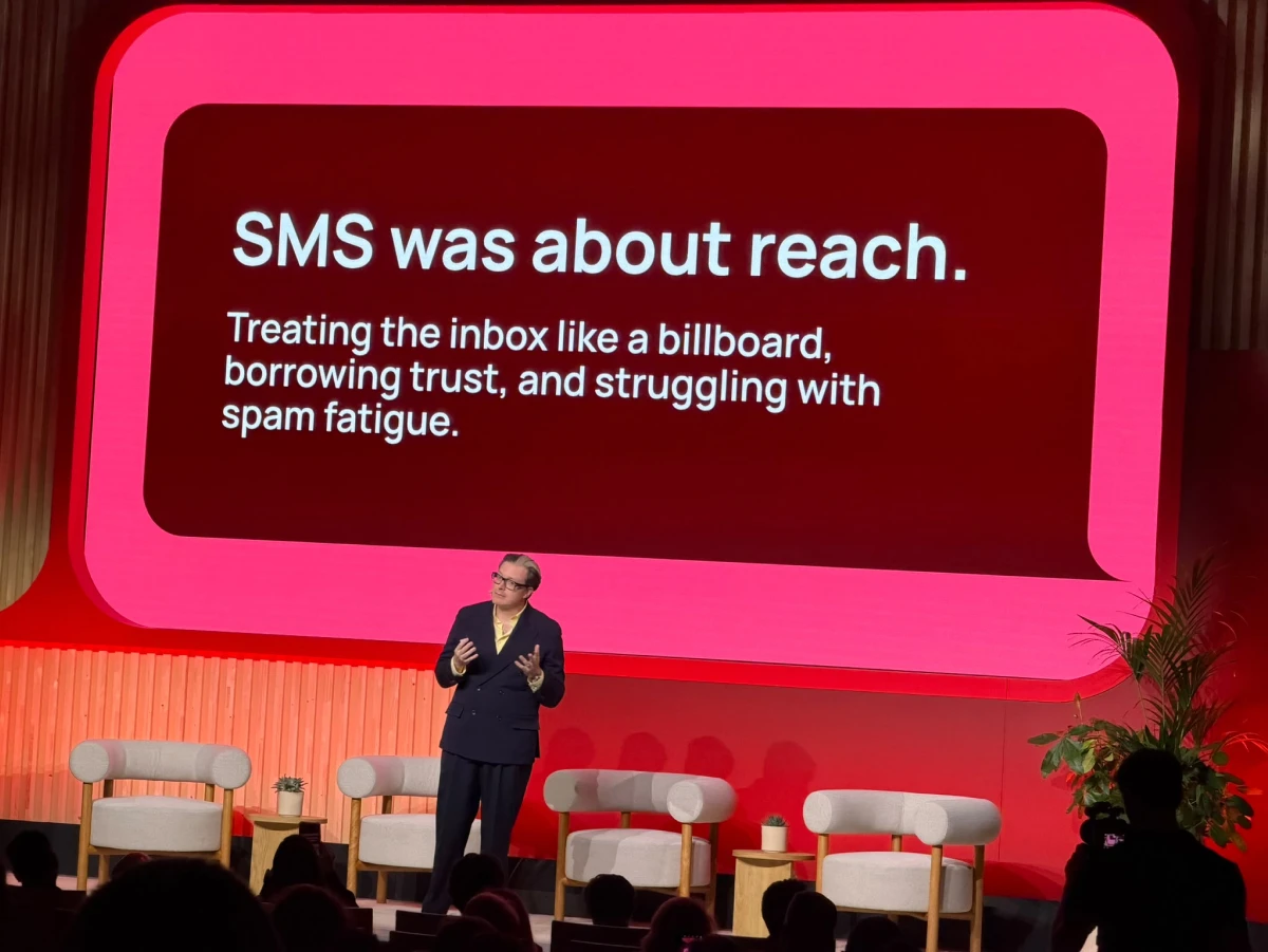 Saal mit Bühne, Keynote-Slide „SMS was about reach" auf der Leinwand